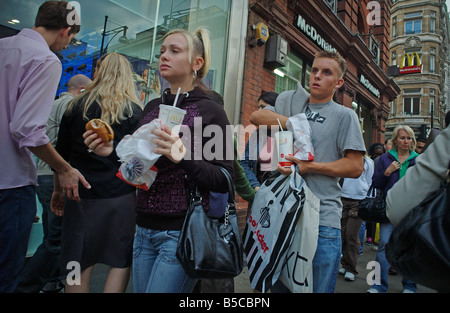 A couple walking down Oxford street eating Fast Food from  McDonalds Stock Photo