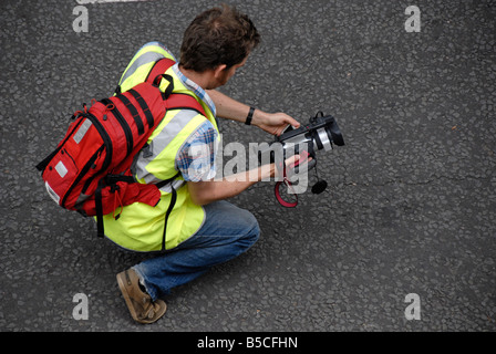 Man kneeling while filming with professional camcorder, Bristol, England, UK Stock Photo