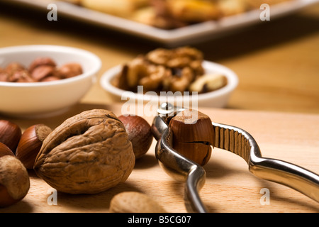 close up of nutcracker, hazelnuts, walnuts, almonds, baked cookies in background Stock Photo
