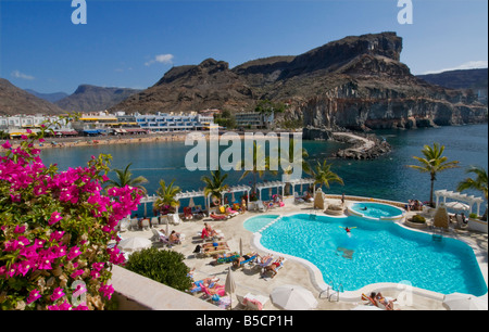 The swimming pool at Club de Mar in Puerto Mogan with sandy Mogan beach, cafes villas behind. Gran Canaria Canary Islands Spain Stock Photo