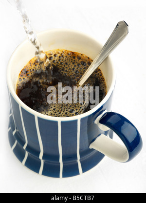 A steaming mug of instant coffee with hot water being poured Stock Photo