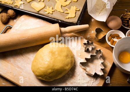 home baking scene - dough, raw christmas cookies on oven rack, various baking ingredients and utensils Stock Photo