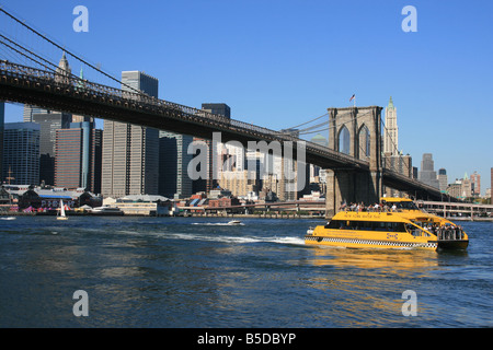 New York Water Taxi passing under the Brooklyn Bridge on the East River Stock Photo