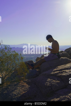 Hiker Mountain Climber With Sun Resting At Peak Of Camelback Mountain, Phoenix, Arizona, USA Stock Photo