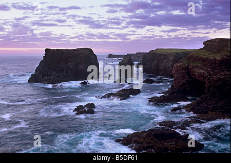 Sunset at Eshaness basalt cliffs, Moo Stack on left, and deeply eroded coast with caves, Northmavine, Shetland Islands, Scotland Stock Photo