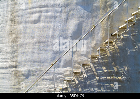 Old Metal Stairs On Side Of White Stucco Storage Tank With Rust Stains, USA Stock Photo