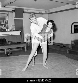 Women's Self Defence: Judo expert Joe Robinson shows Valerie Dave some self defence moves on a willing volunteer. February 1957 Stock Photo