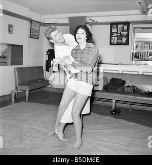 Women's Self Defence: Judo expert Joe Robinson shows Valerie Dave some self defence moves on a willing volunteer. February 1957 Stock Photo