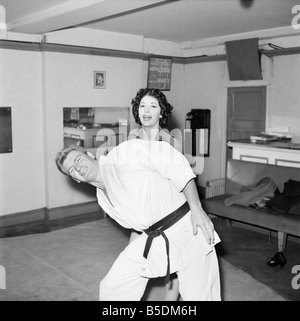 Women's Self Defence: Judo expert Joe Robinson shows Valerie Dave some self defence moves on a willing volunteer. February 1957 Stock Photo