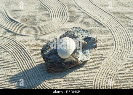 Stones stacked on top of driftwood on raked sand Stock Photo
