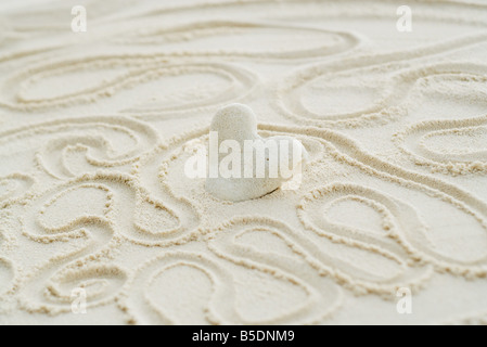 Heart-shaped coral stuck in sand, surrounded by squiggly lines Stock Photo