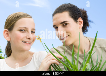 Young man and preteen girl with flowering aloe plant, smiling at camera Stock Photo