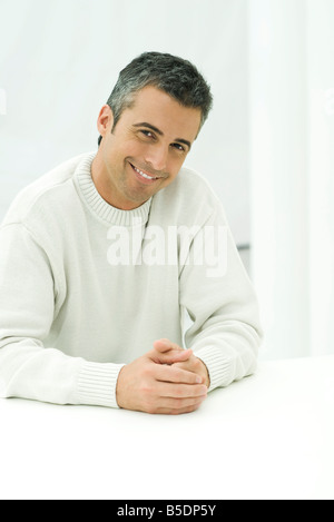 Man sitting with hands together, smiling at camera, portrait Stock Photo