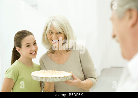 Grandmother and granddaughter side by side, senior woman holding pie Stock Photo