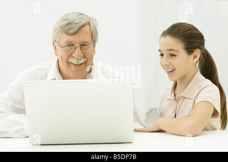 Grandfather and granddaughter looking at laptop together Stock Photo
