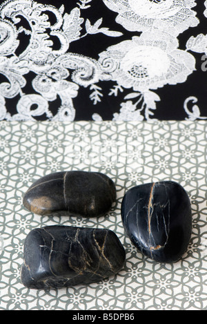Three polished pebbles arranged against patterned background Stock Photo
