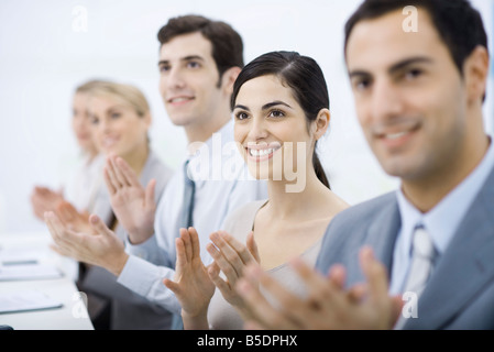 Group of professionals clapping, smiling, focus on one woman Stock Photo