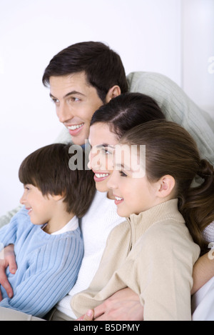 Man embracing his wife and children, all looking away and smiling Stock Photo