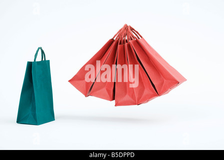 Group of red shopping bags floating in midair beside single blue bag Stock Photo