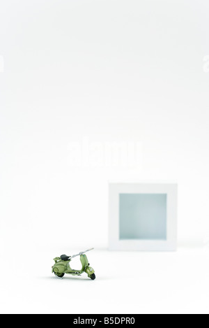 Miniature scooter parked with square object in background Stock Photo