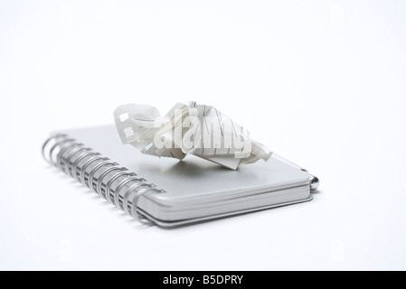 Crumpled paper resting on cover of closed notebook, close-up Stock Photo