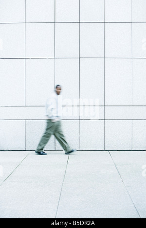 Man walking with hands in his pockets down sidewalk Stock Photo
