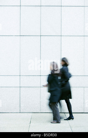 Two businesswomen walking side by side down sidewalk Stock Photo