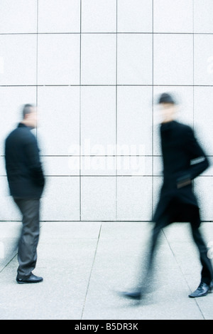 Two men passing one another as they walk along the sidewalk