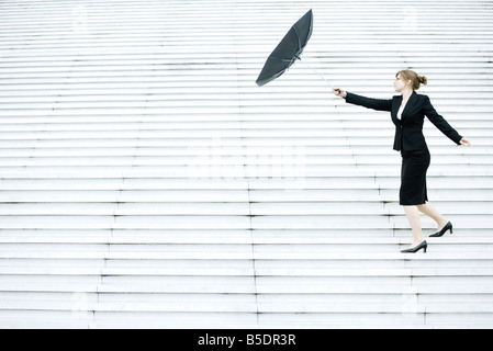 Businesswoman struggling with umbrella in wind Stock Photo