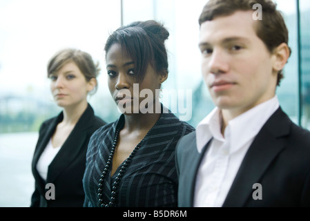 Three business associates standing side by side looking at camera Stock Photo