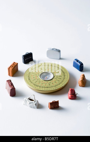 Miniature suitcases and bags arranged around Feng Shui compass Stock Photo