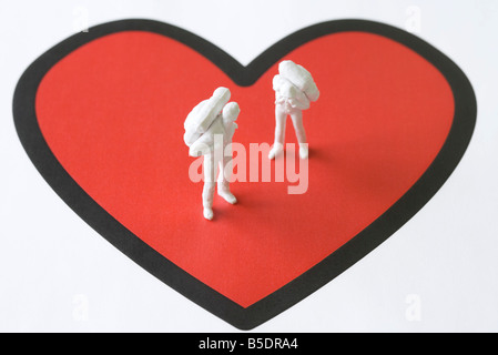Miniature figures standing on large heart Stock Photo