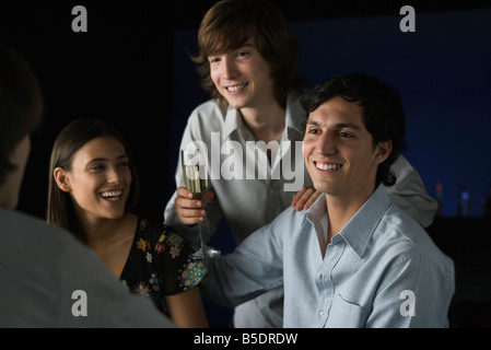 Friends laughing, one holding glass of champagne Stock Photo