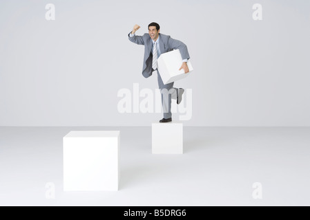 Businessman holding pedestal block, shaking fist Stock Photo