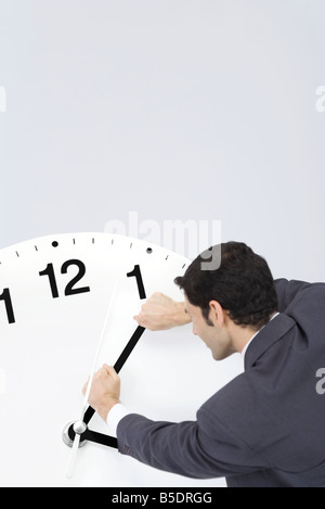 Businessman trying to turn back hands of clock Stock Photo