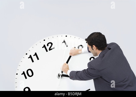 Businessman pushing back hands of clock Stock Photo