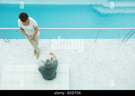 Mature couple relaxing on poolside balcony, overhead view Stock Photo