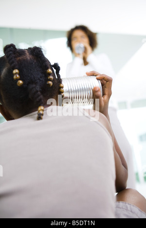 Young girl and woman playing with tin can phone Stock Photo