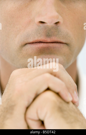 Man holding hands together under chin, cropped view Stock Photo