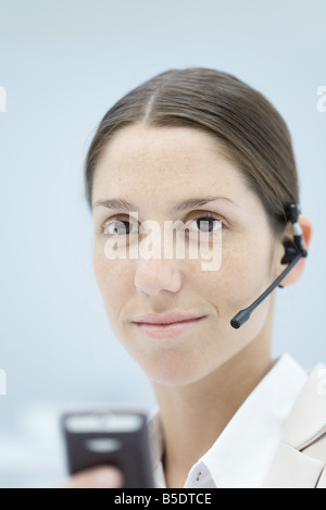 Young woman wearing headset, smiling, portrait Stock Photo