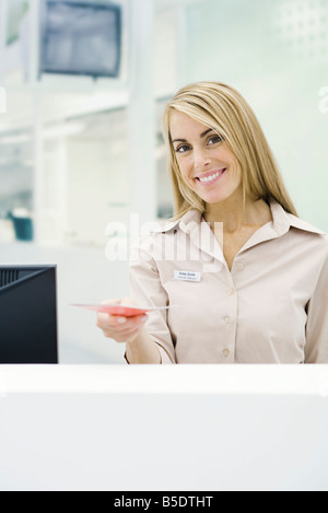 Professional woman holding out brochure, smiling at camera Stock Photo