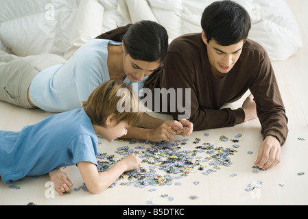 Family lying on floor, putting together jigsaw puzzle Stock Photo