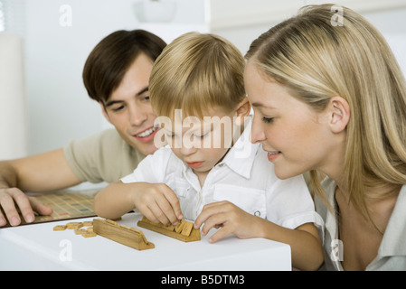 Parents watching as little boy arranges game pieces Stock Photo