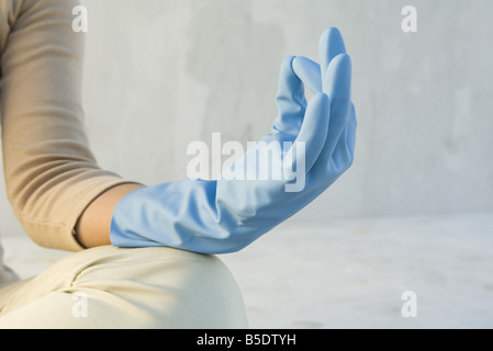 Person meditating with hand in mudra position, wearing rubber glove, cropped view Stock Photo