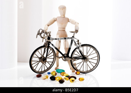 Wooden figurine holding racing cycle, in foreground pills Stock Photo