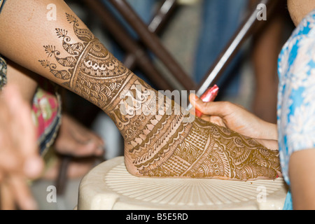 a Henna tatoo (mehendi )is being applied to the foot of a young Indian bride Stock Photo