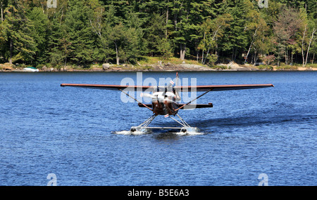 A single engine float plane taxing to the dock on Long Lake New York ...