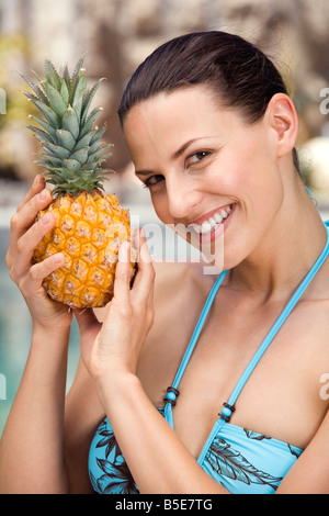 Young woman in bikini holding ananas, portrait Stock Photo