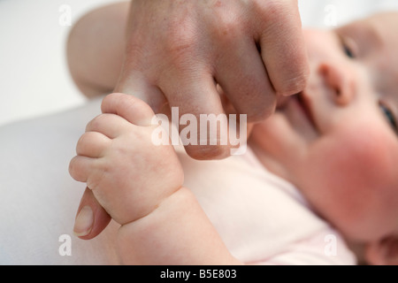 Everyday scene of a baby girl aged three months holding mother's finger. England, UK Britain Stock Photo