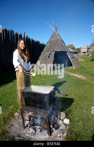 Indian Native woman roasting corn on open fire Corn Roost at Huron Indian Village in Midland Ontario Canada Stock Photo